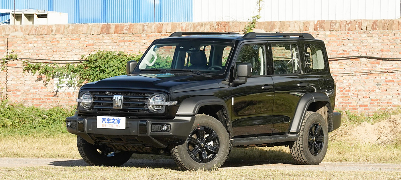 TANK 300 припаркованный на траве, на фоне кирпичной стены и промышленных зданий.